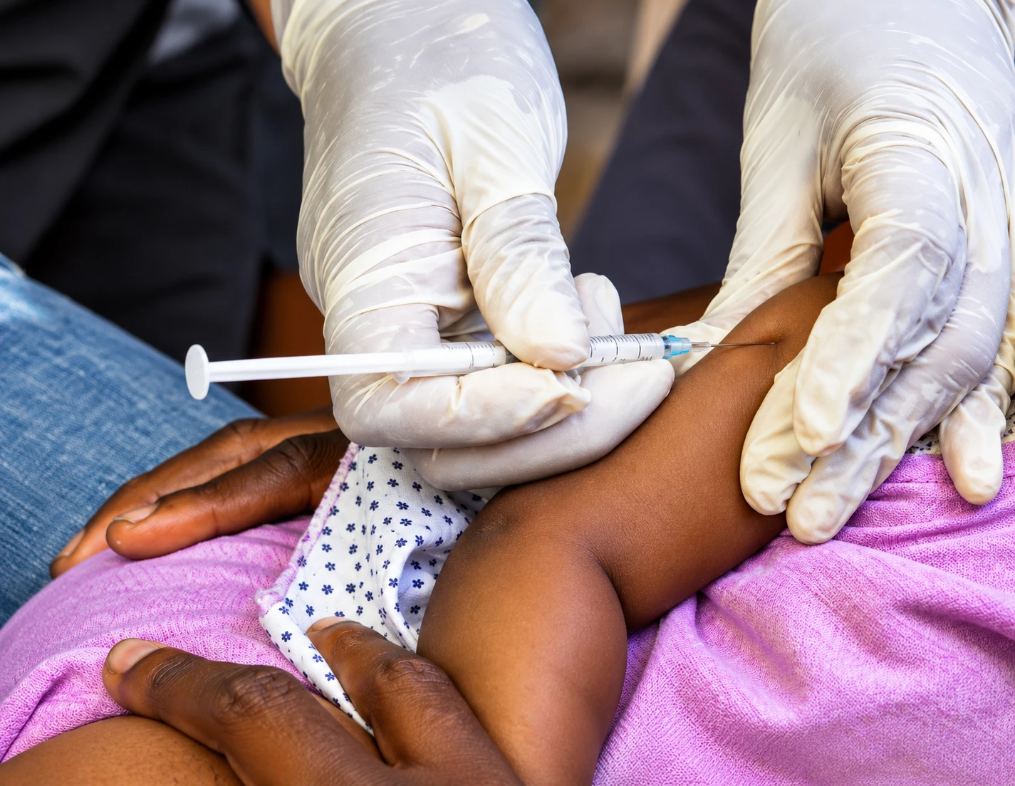 A health worker in gloves vaccinating a child